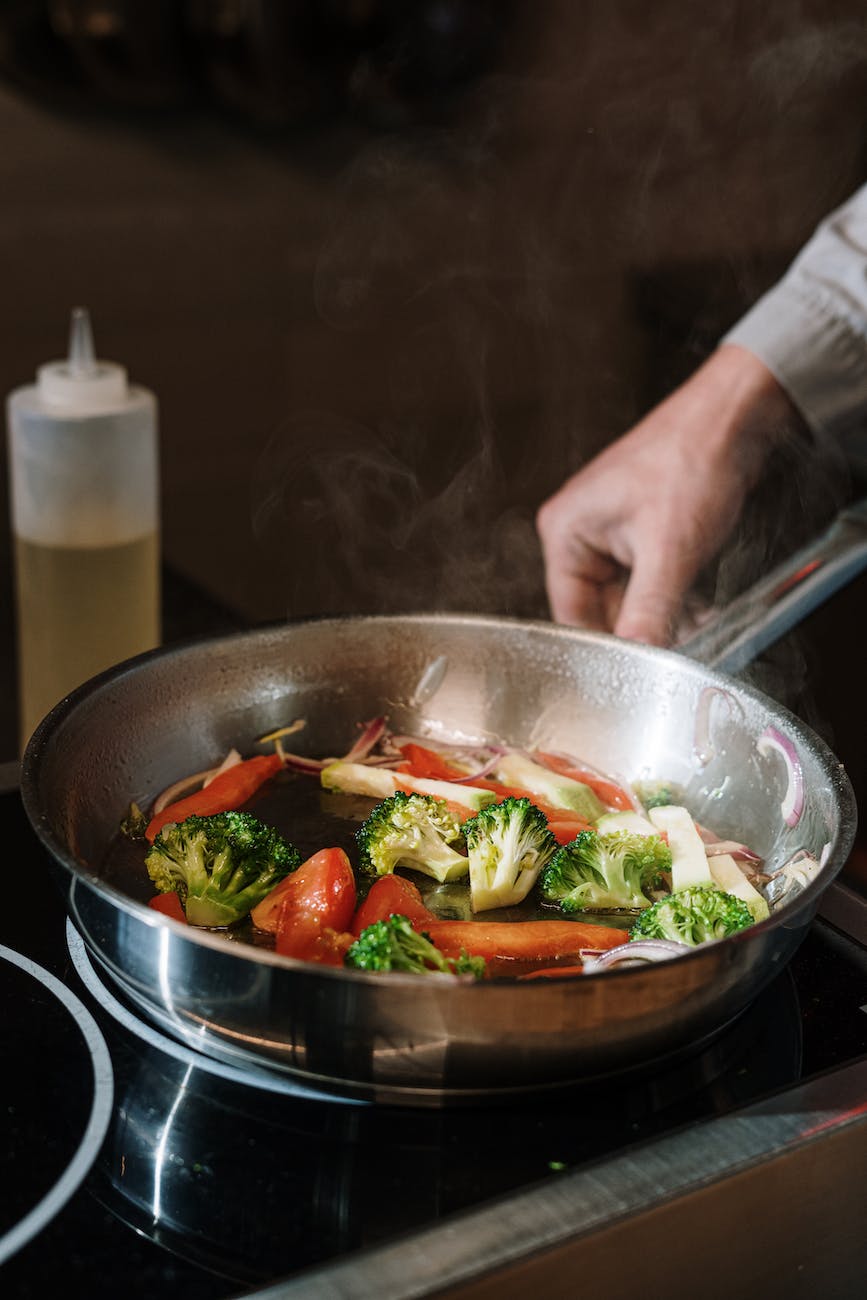 person holding black cooking pan with vegetable salad was kostet eine gute bratpfanne